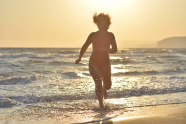 Kırmızı bir mayo içinde sahilde poz güzel mutlu esmer kız.