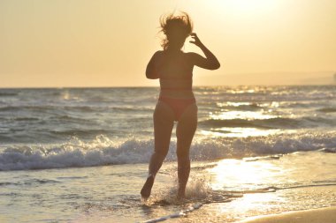 Kırmızı bir mayo içinde sahilde poz güzel mutlu esmer kız.