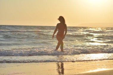 Kırmızı bir mayo içinde sahilde poz güzel mutlu esmer kız.