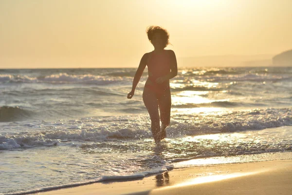 Kırmızı bir mayo içinde sahilde poz güzel mutlu esmer kız.