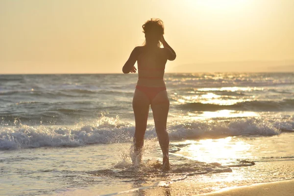 Kırmızı bir mayo içinde sahilde poz güzel mutlu esmer kız.
