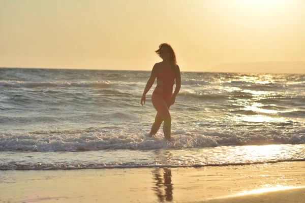 Kırmızı bir mayo içinde sahilde poz güzel mutlu esmer kız.