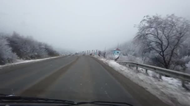 Автомобиль на зимней горной дороге засыпает снегом — стоковое видео