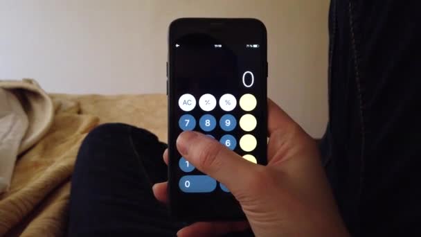 Empresario en casa en la cama considera calculadora en el teléfono — Vídeo de stock