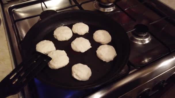 Jovem mulher faz panquecas de queijo cottage no fogão de cozinha — Vídeo de Stock