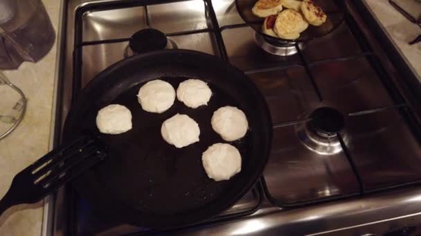 Jovem mulher faz panquecas de queijo cottage no fogão de cozinha — Vídeo de Stock