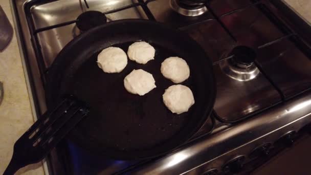 Mujer joven hace panqueques de queso cottage en la cocina estufa — Vídeos de Stock