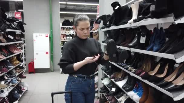 Young Woman Shoe Shop Examines Ankle Boots — Stock Video