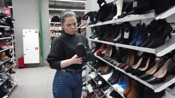 Mujer Joven Una Zapatería Examina Las Botas Tobillo — Vídeo de stock