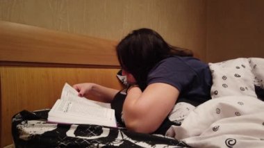 Kapa çeneni. Okumak için bir kitap yatakta yatıyordu güzel esmer kız. Genç bir kadın ilginç bir kitap açılır.