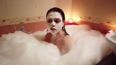 Kadın alarak banyoda küvet, banyo 4k. O aplying yüz kil maskesi.