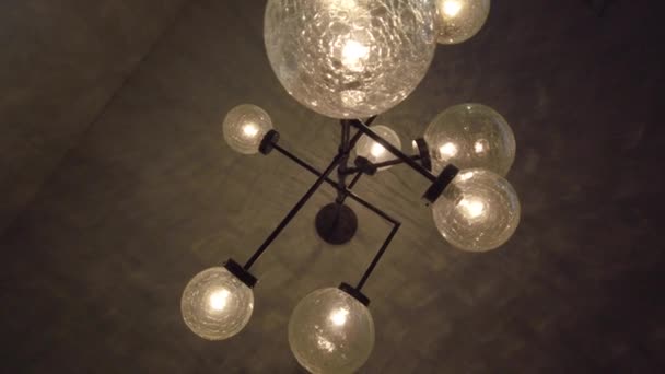 Decorative lighting bulbs hanging on ceiling. Bright glowing light from vintage bulbs lamp. Antique tungsten light lamp on ceiling in dark room. Lighting interior design. Vintage chandelier decor — Stock Video