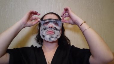 Kadın yatakta yüzündeki akşamları kağıt maske uygulamak