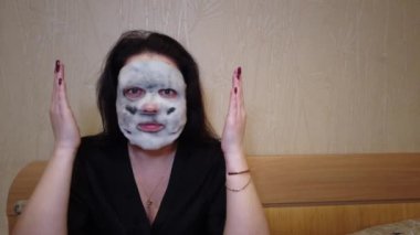 Kadın yatakta yüzündeki akşamları kağıt maske uygulamak