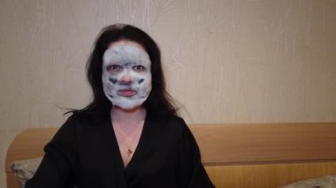 Kadın yatakta yüzündeki akşamları kağıt maske uygulamak