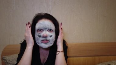 Kadın yatakta yüzündeki akşamları kağıt maske uygulamak