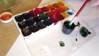 Kadın eller renkli gökkuşağı boyama. Çeşitli fırçalar, boyalar ve boya kalemleri ile boyama için ayarlayın. Üst görünüm