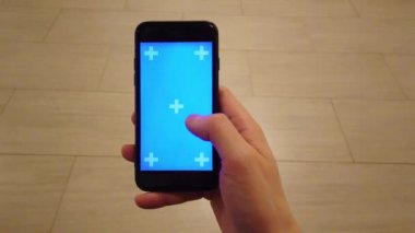 Genç adam Smartphone tutuyor. Dokunmatik ekran kullanarak, dokunun, mavi ekranda el hareketlerini tokatlamak.