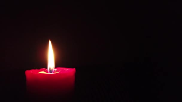 Bougie rouge brûlante avec flamme scintillante sur fond sombre .