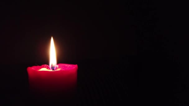 Bougie rouge brûlante avec flamme scintillante sur fond sombre .