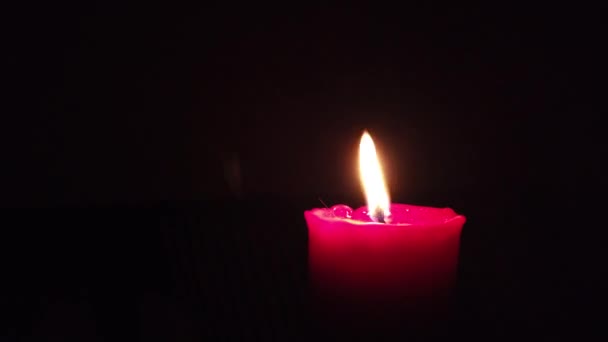 Bougie rouge brûlante avec flamme scintillante sur fond sombre .