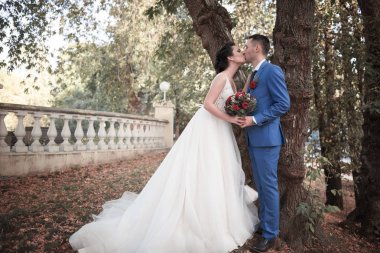 Evlilik çift niteliğine birbirlerine sarılıyor. Beyaz elbiseli güzel model kız. Takım elbiseli adam. Güzellik gelinle damat. Kadın ve erkek portre. Dantel örtü ile kadın. Kadın ve adam açık havada