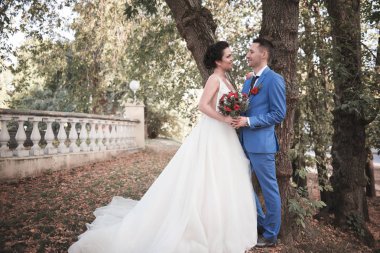 Evlilik çift niteliğine birbirlerine sarılıyor. Beyaz elbiseli güzel model kız. Takım elbiseli adam. Güzellik gelinle damat. Kadın ve erkek portre. Dantel örtü ile kadın. Kadın ve adam açık havada