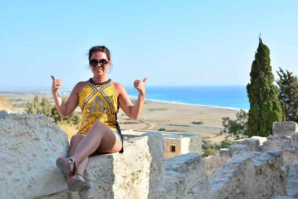 La chica se sienta en un acantilado bajo un viejo árbol con una hermosa vista del mar y las montañas. Vacaciones en el resort europeo. Viajes y ocio . — Foto de Stock