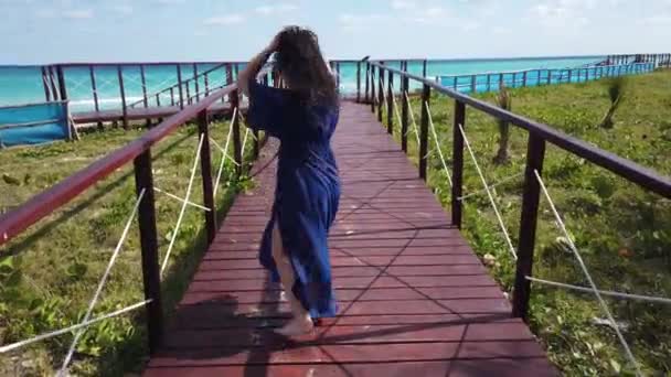 白い熱帯のビーチとターコイズブルーの海に向かう途中のバラデロの木製の橋の女の子 — ストック動画