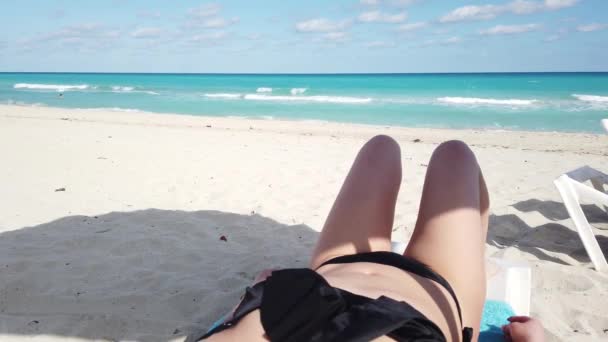 ビーチのデッキチェアに横たわる美しいブルネットの女性のクローズアップ 背景に海とエキゾチックな場所で日光浴 — ストック動画