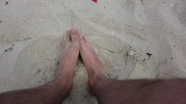Bir insanın ayakları yaz mevsiminde kumsalda kum karıştırıyor. Kum kıyısı. Denizde dinlen..