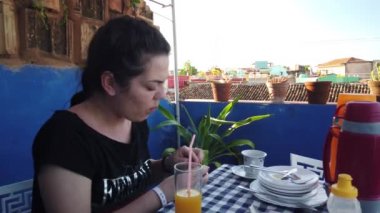 Güzel genç kadın doğada bir evin yanında bir sigara içiyor. Verandada Kahvaltı Olan Kız.