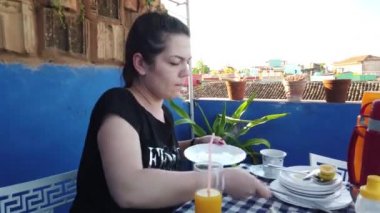 Güzel genç kadın doğada bir evin yanında bir sigara içiyor. Verandada Kahvaltı Olan Kız.