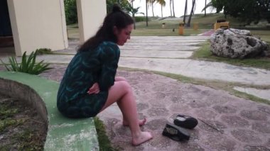 Tatil köyünde dinlenmiş bir kız. Otelde palmiye ağaçlarında dinlenin. Kız oturma ve tvening sessiz dinlenme.