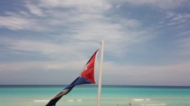 Sahilde Küba bayrağı, okyanusun arka planında rüzgarda uçuyor. Küba, Varadero.
