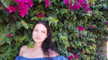 Genç çekici esmer kadın parkta kırmızı bahar çiçekleri arka planda yürüyor. Elinde kırmızı çiçekler olan kız.