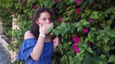 Genç çekici esmer kadın parkta kırmızı bahar çiçekleri arka planda yürüyor. Elinde kırmızı çiçekler olan kız.