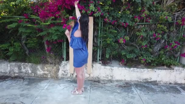 Young attractive brunette woman walks on the background of red spring flowers in park. Girl with red flowers in her hands. — Stock Video