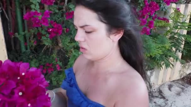 Ung attraktiv brunett kvinna går på bakgrunden av röda våren blommor i parken. Flicka med röda blommor i händerna. — Stockvideo