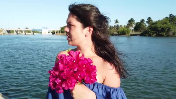 Jonge aantrekkelijke brunette vrouw loopt op de achtergrond van rode lente bloemen in Park. Meisje met rode bloemen in haar handen. — Stockvideo