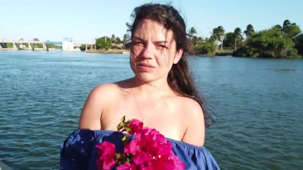 Young attractive brunette woman walks on the background of red spring flowers in park. Girl with red flowers in her hands. — Stock Video