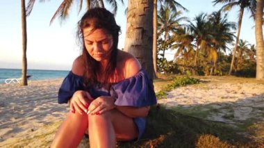 Gün batımında sahilde palmiye ağacının yanında esmer kız