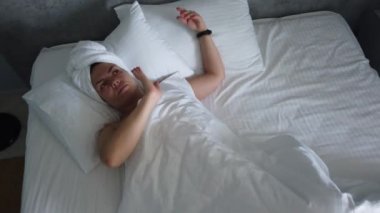 Güzel genç kız beyaz bir yastık üzerinde uyuyor. O uyanma, germe ve gülümseyerek. El gerçek zamanlı orta atış