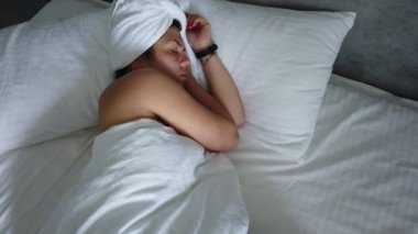 Güzel genç kız beyaz bir yastık üzerinde uyuyor. O uyanma, germe ve gülümseyerek. El gerçek zamanlı orta atış