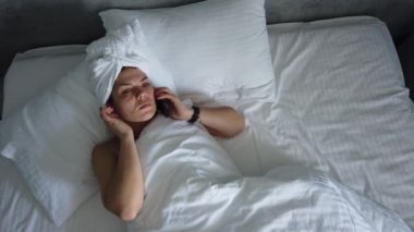 Üst görünümü genç kadın battaniye altında yatakta uyanma. Sevimli kız sabah ilk şey onu akıllı telefon kontrol.