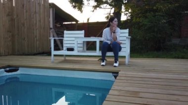 Kız yüzme havuzunda sigara içiyor. Havuz başında akşam dinlenen kız