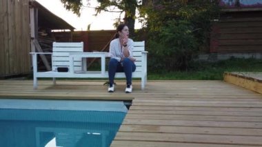 Kız yüzme havuzunda sigara içiyor. Havuz başında akşam dinlenen kız