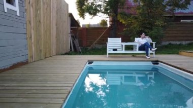 Kız yüzme havuzunda sigara içiyor. Havuz başında akşam dinlenen kız