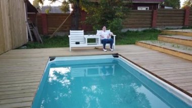 Kız yüzme havuzunda sigara içiyor. Havuz başında akşam dinlenen kız