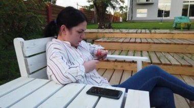 Cep telefonu kadın kullanımı ve bahçesinde evde bankta oturup